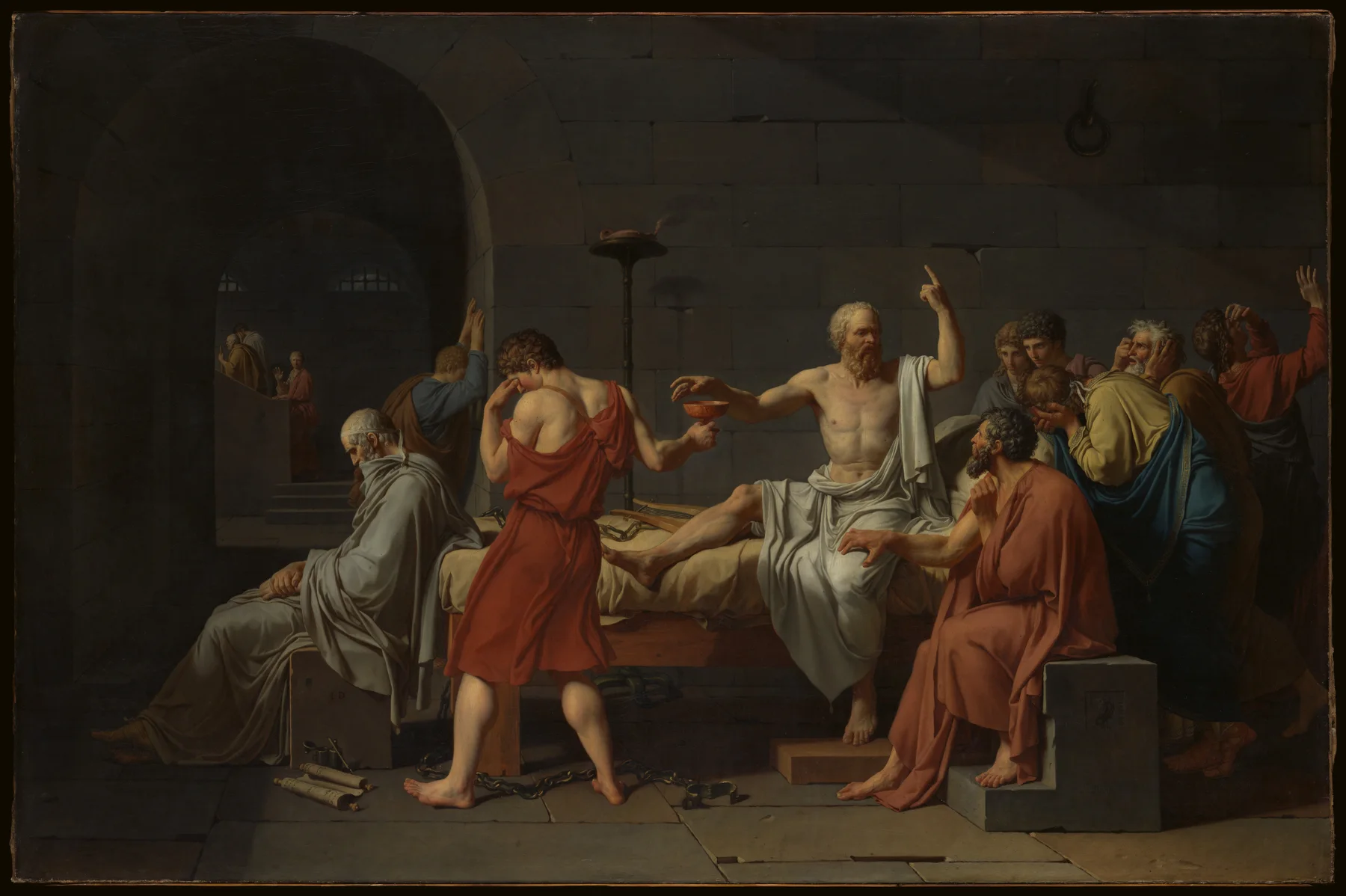 Socrates reaches for a cup of hemlock while his companions grieve.